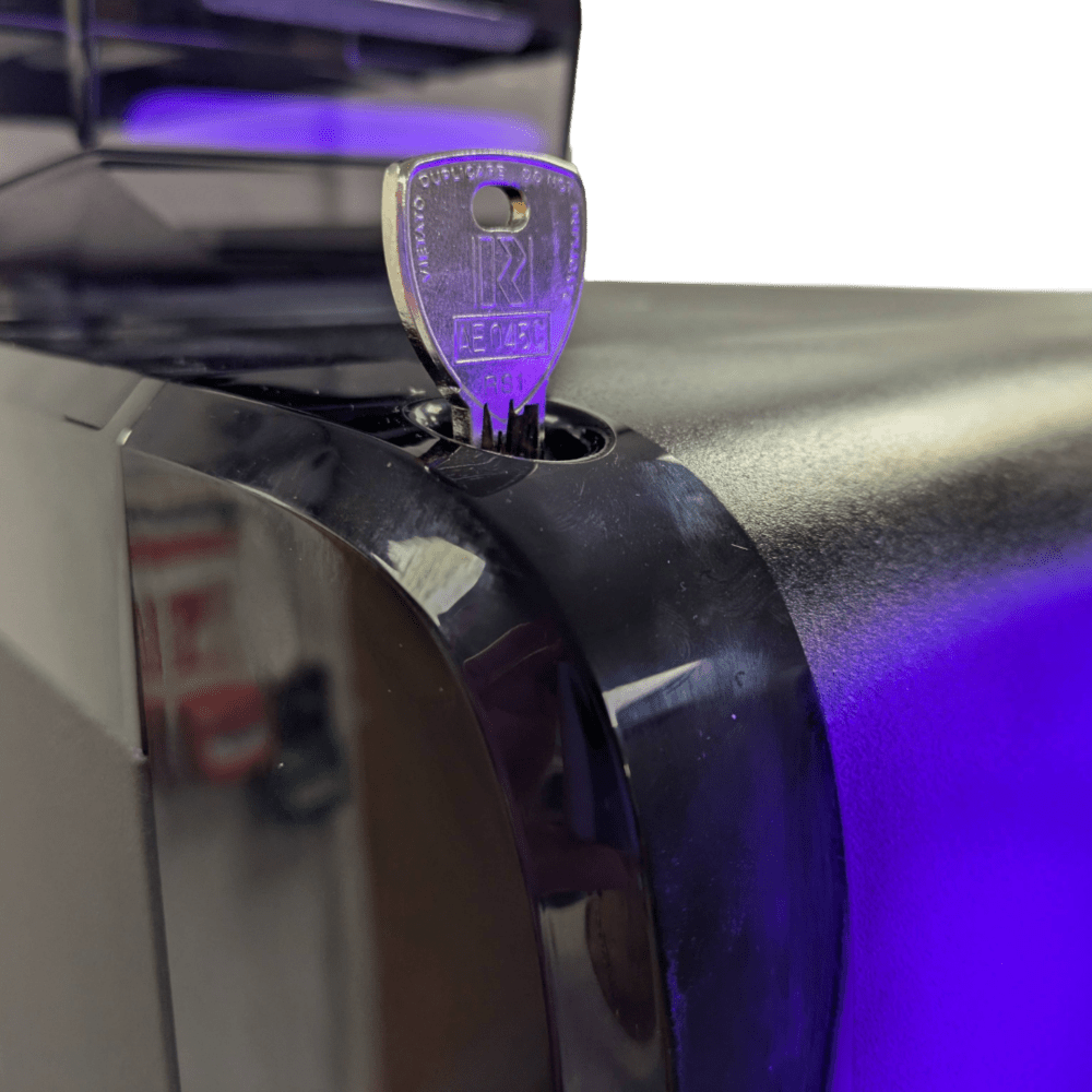 Close-up of OBL1 coffee machine door lock with key inserted and purple accent lighting on the chrome surface
