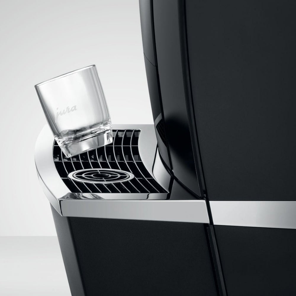 Side view of OBL2 Jura Giga X8C showing its sleek black drip tray and a Jura glass resting on it
