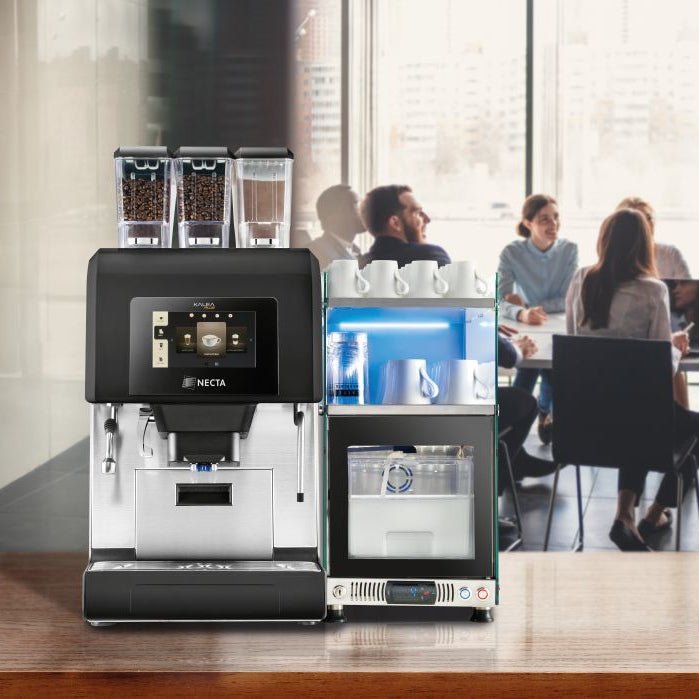 OBL3 Kalea Plus coffee machine with three bean hoppers and milk fridge on a wooden table in an office meeting room with people in the background