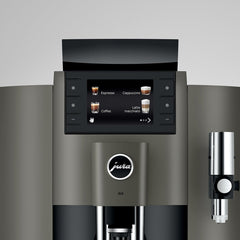 Close-up of OBS1 coffee machine touchscreen showing drink selections with Jura logo and steam wand on a gray background