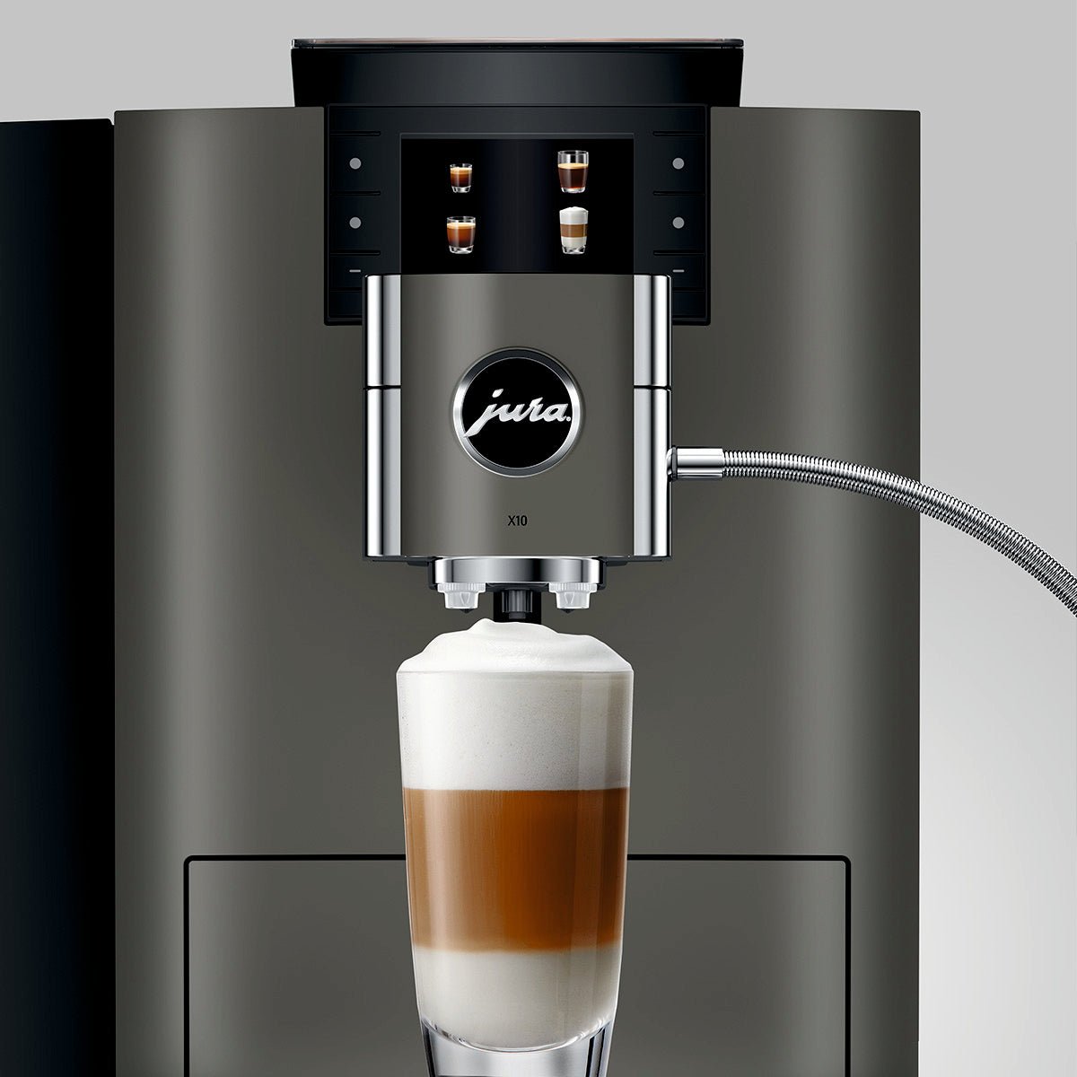 Close-up of OBM3  Jura X10 coffee machine spout dispensing a layered latte into a glass with milk foam on a dark grey background