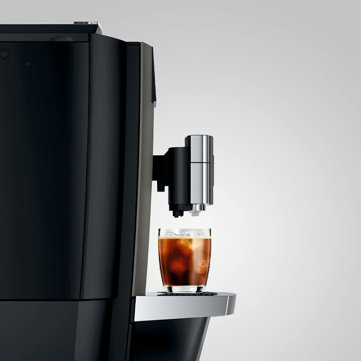 Left view of OBM3  Jura X10 coffee machine dispensing a glass of iced coffee into a clear cup on a light gray background