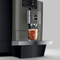 Side view of OBM3 Jura X10 coffee machine dispensing iced coffee into a glass on a light gray background